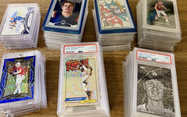 Stacks of graded cards including a PSA 10 2024 Mosaic Drake Maye, PSA 10 Travis Kelce Black Color Blast, PSA 10 2018 Kaboom Kevin Durant and a PSA 9 2025 Topps Chrome Shohei Ohtani World Series at Night, from the Conroe Card Show in January 2026