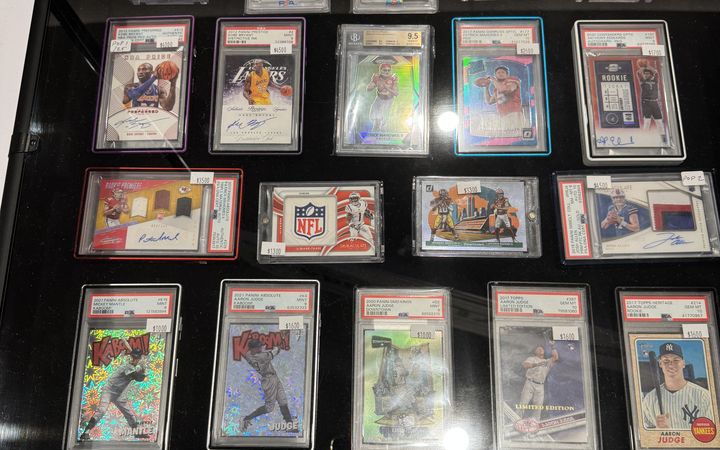 A display case of graded slabs at the Conroe Card Show, October 2025, including Kaboom inserts, Downtowns, Kobe Bryant autographs, Patrick Mahomes rookies and Aaron Judge cards