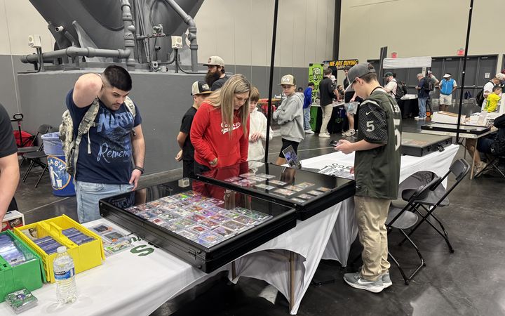 Collectors browsing the Slabs & Signatures cases at the H-Town Card Show in the George R. Brown Convention Center, January 2026, with Grayson working the table